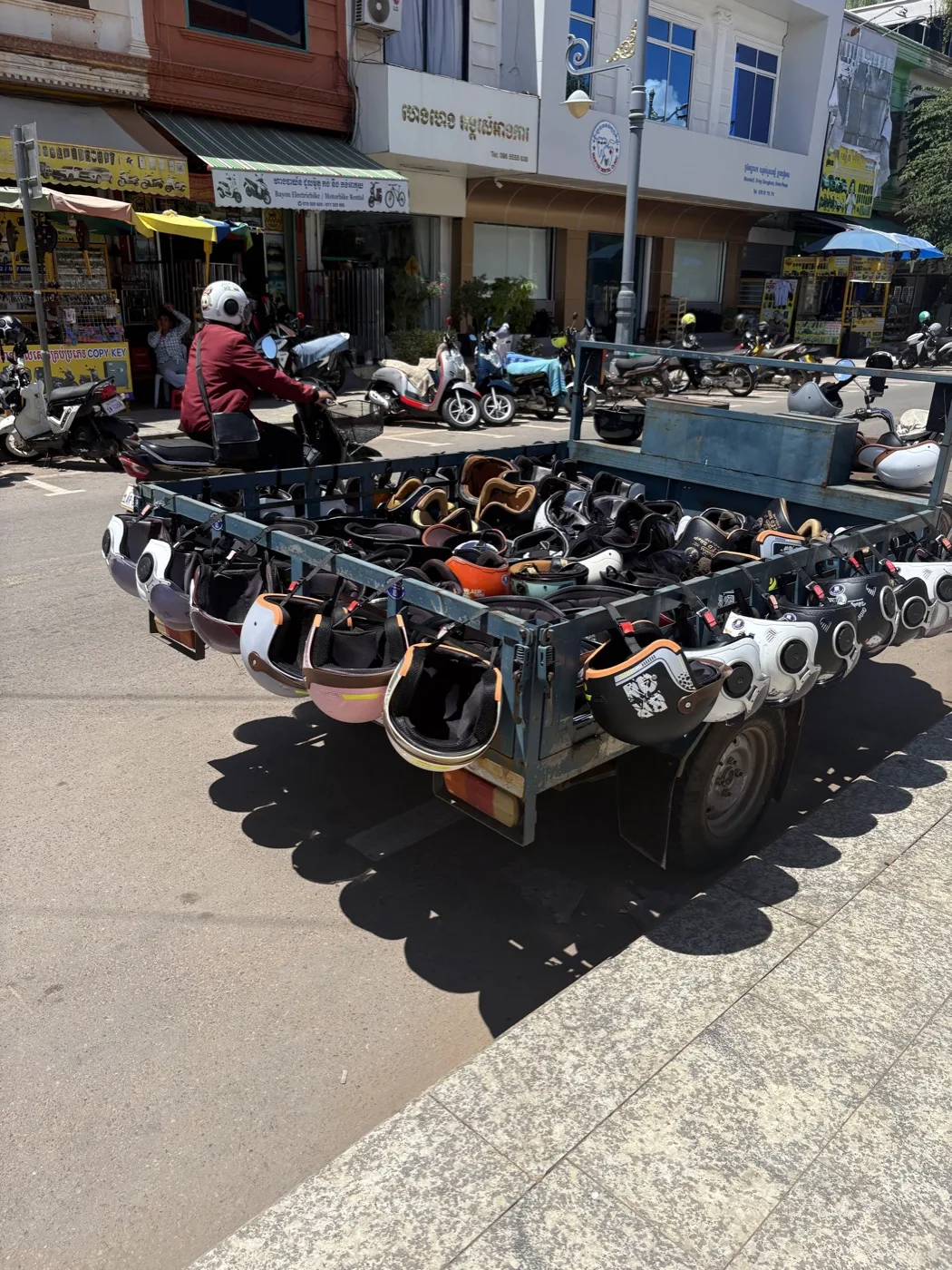 Cart loaded with motorcycle helmets on a busy Cambodian street