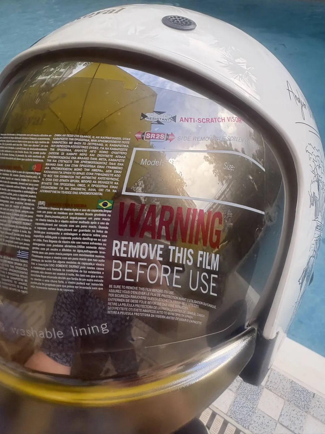 Helmet visor showing multilingual safety certifications and instructions