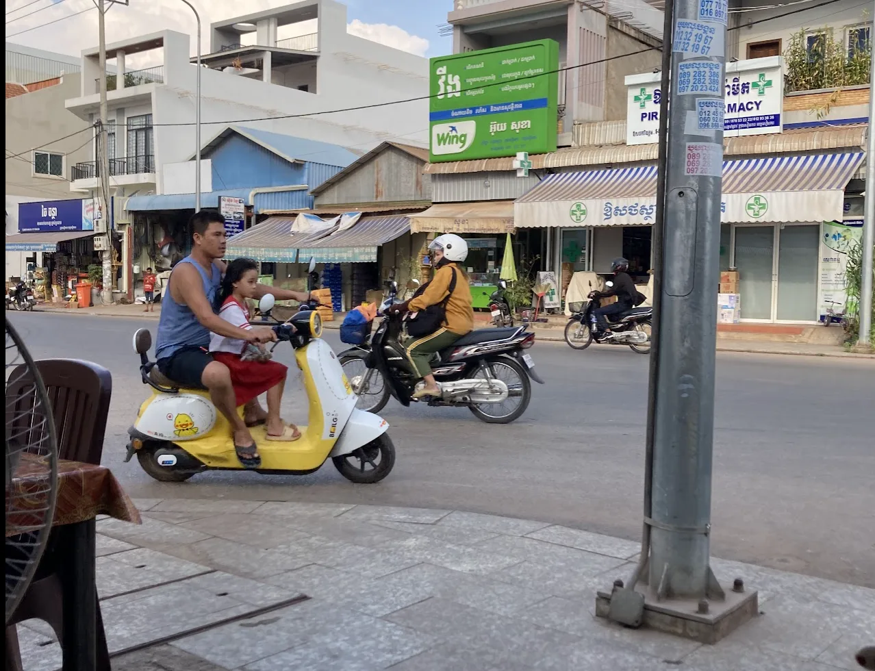 Family on a scooter with child wearing a yellow helmet in Cambodia