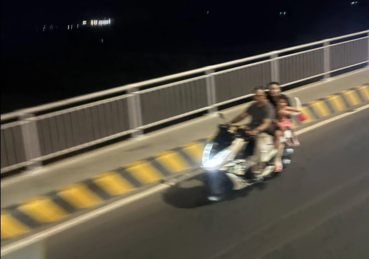 Family of four on a motorcycle at night on a bridge, motion blur, no helmets
