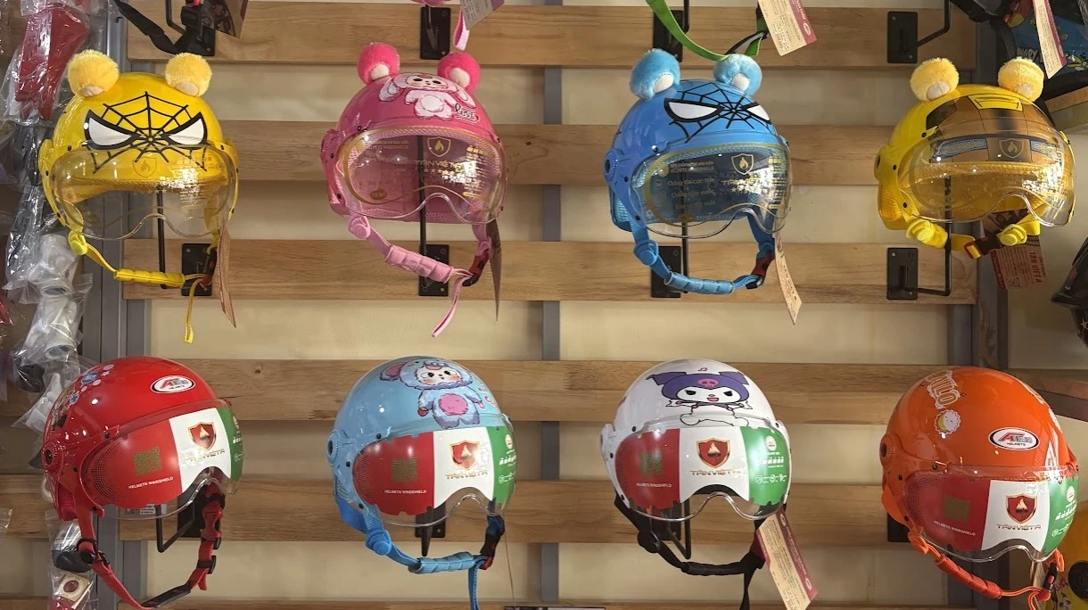 Eight children's helmets displayed on a rack in a Cambodian helmet shop