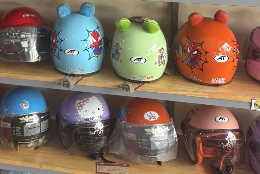 Shelf of colorful children's character helmets in a Cambodian helmet shop