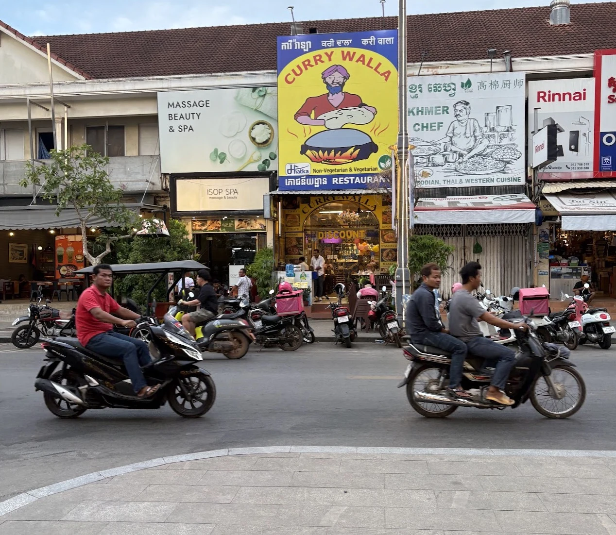 Busy Siem Reap intersection with multiple riders and passengers, none wearing helmets