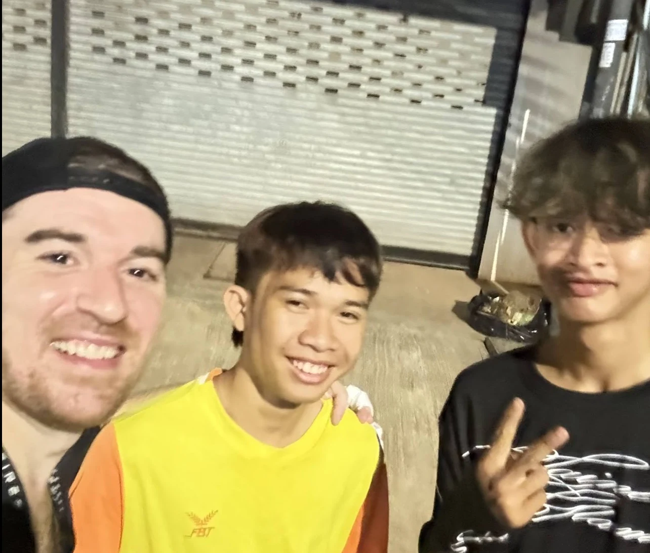 Jim smiling with two young Cambodian men at night