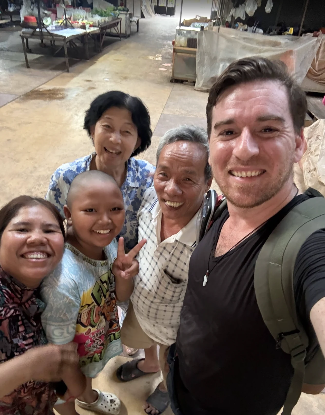 Jim taking a selfie with a Cambodian family smiling together in a local market
