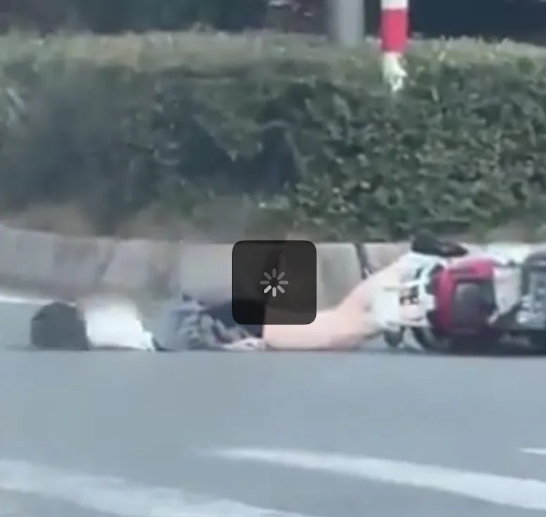 Helmeted motorcycle rider lying beside a motorcycle after a road crash