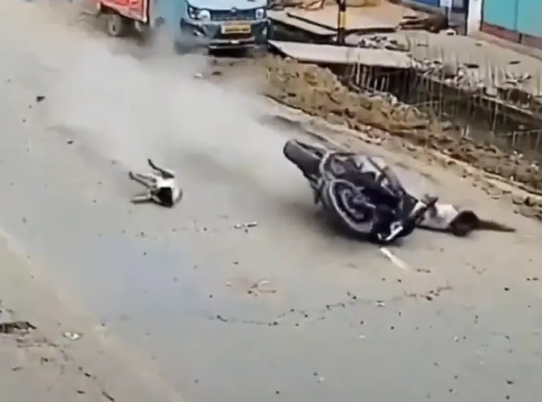 Motorcycle and injured rider lying on a roadway after a crash