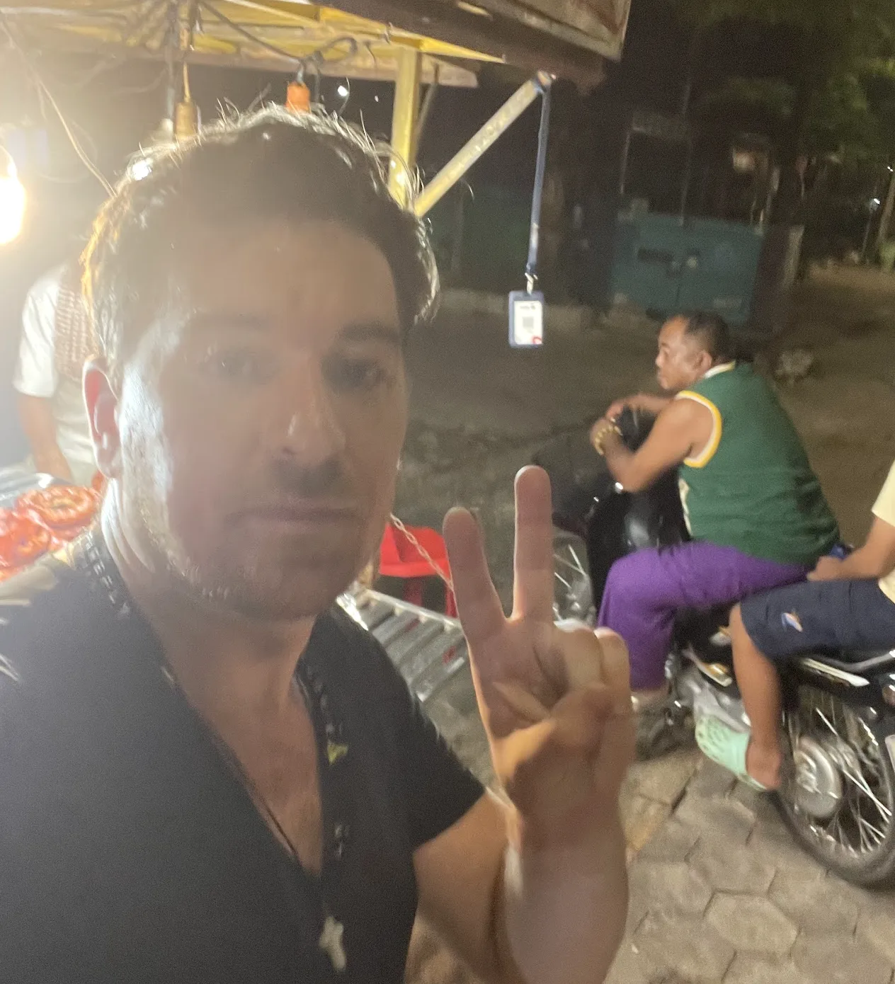 Jim engaging with a young child on a motorcycle at night during outreach in Cambodia
