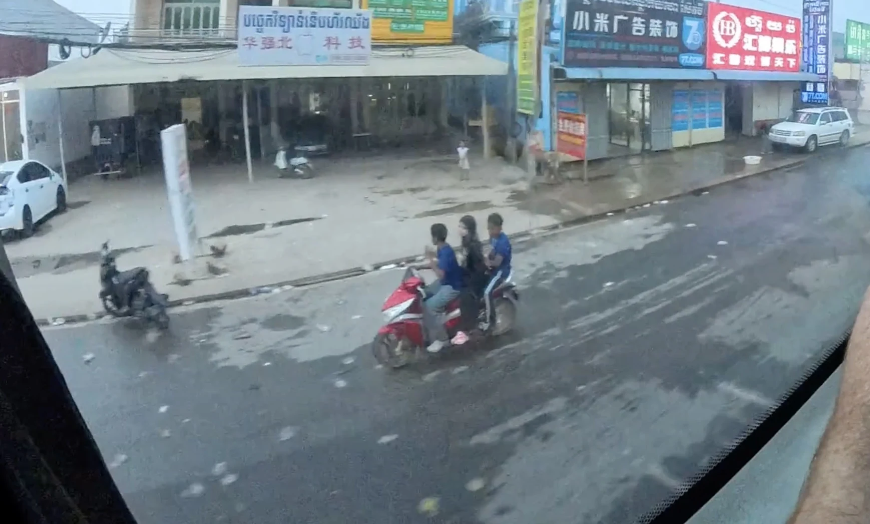 Three riders on a motorcycle in the rain without helmets